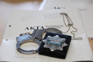 Policyjna odznaka, kajdanki oraz obwoluta