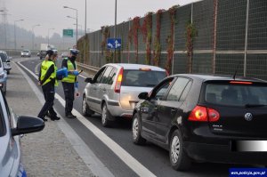 na drodze zatrzymane dwa pojazdy obok dwoje funkcjonariuszy i pracownik komisji